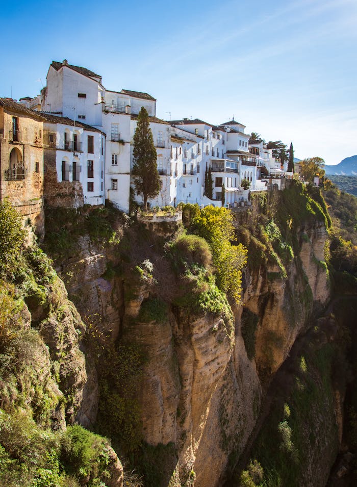 Scenic view of Ronda's historic cliffside buildings in Spain, surrounded by natural beauty.
