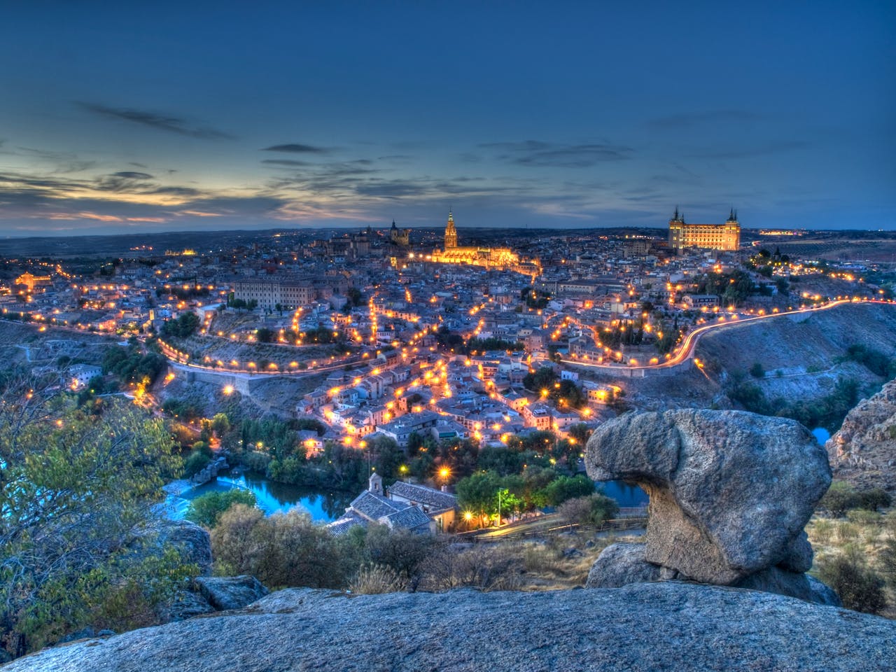 A breathtaking twilight cityscape view of Toledo, Spain, with dramatic evening lights.